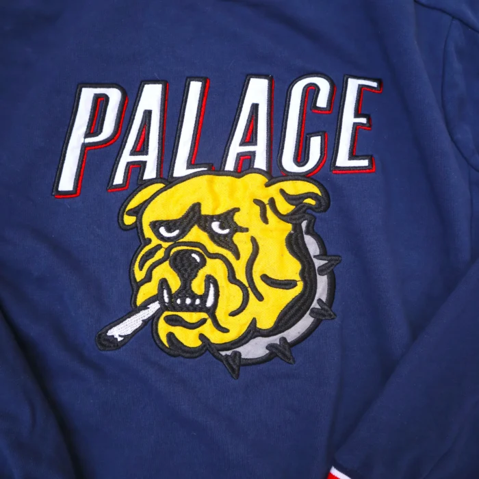 This vintage Palace crewneck stands out with its bold graphic and premium construction. The navy blue fabric is contrasted by red and white striped ribbing on the collar, cuffs, and hem for a classic, sporty look.